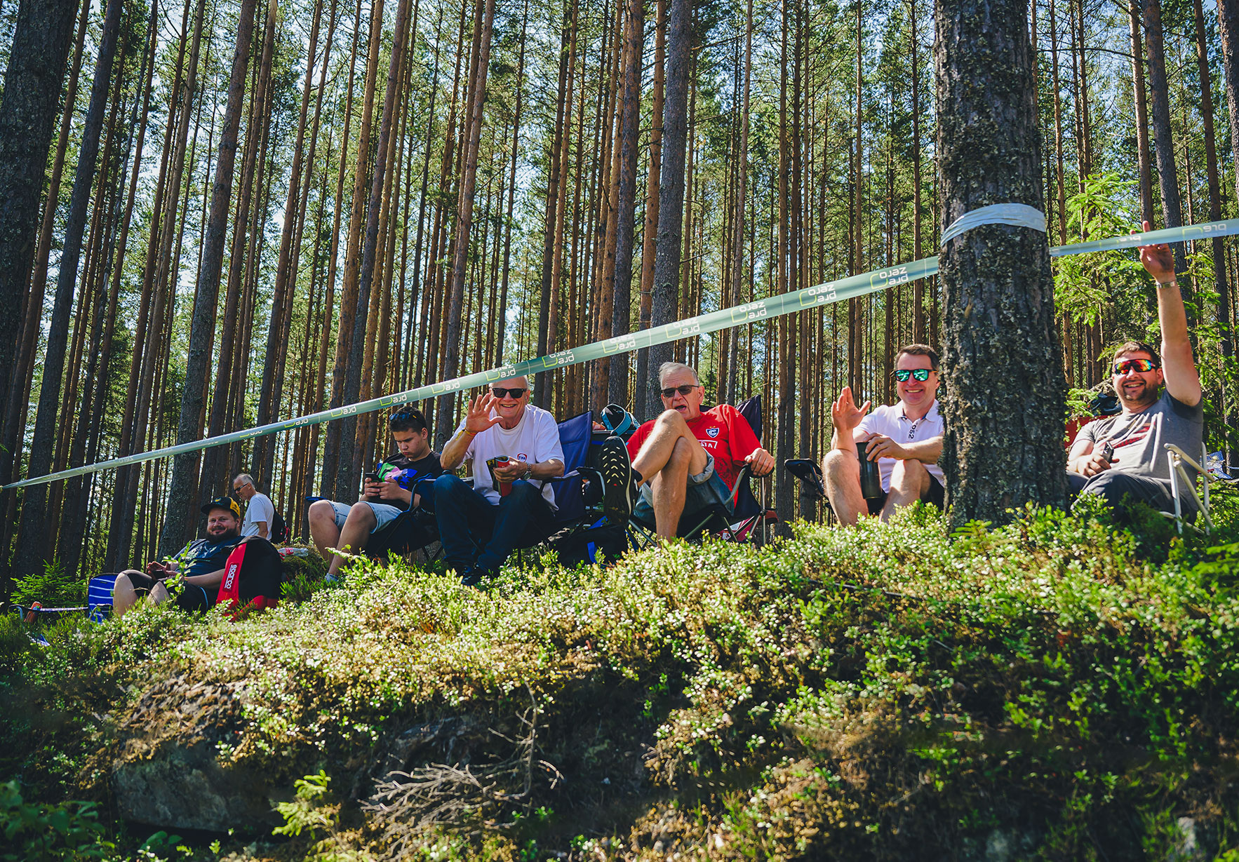 publik som sitter på stolar i blåbärsris i skogen